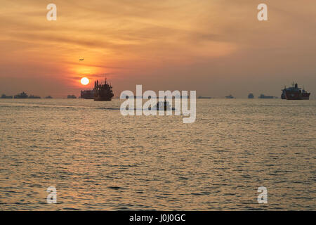 Le lever du soleil sur les navires à l'ancre dans le détroit de Singapour. Banque D'Images