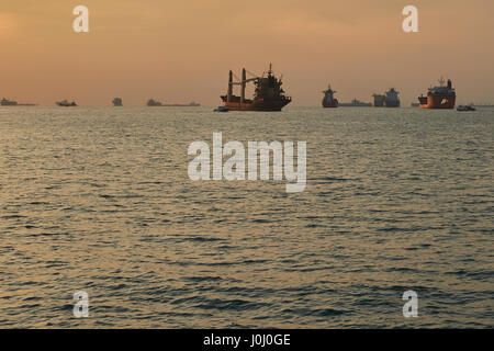 Le lever du soleil sur les navires à l'ancre dans le détroit de Singapour. Banque D'Images