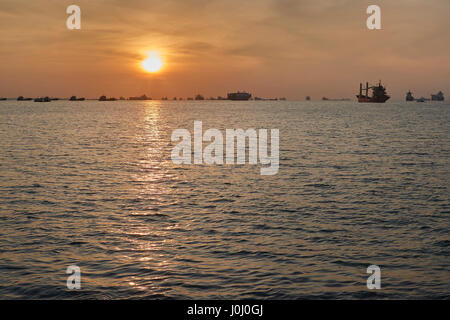 Le lever du soleil sur les navires à l'ancre dans le détroit de Singapour. Banque D'Images