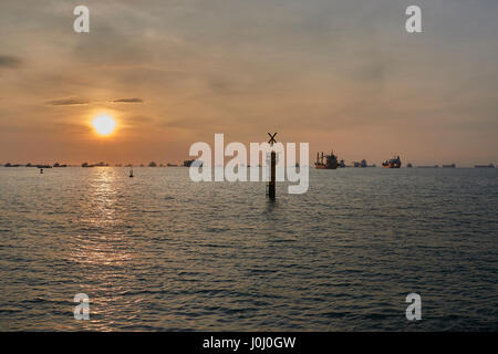 Le lever du soleil sur les navires à l'ancre dans le détroit de Singapour. Banque D'Images