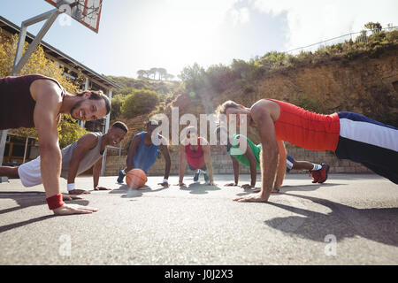 Les joueurs de basket-ball faisant des pompes jusqu'à l'exercice de basket-ball extérieur Banque D'Images