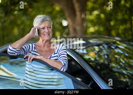 Agacé senior Woman talking on phone en voiture Banque D'Images