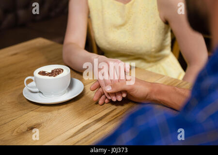 Close up of couple holding hands par tasse de café à la table à café shop Banque D'Images