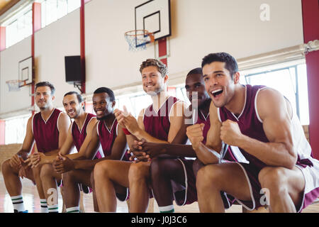 Joueur de basket-ball excités assis sur un banc en cour Banque D'Images
