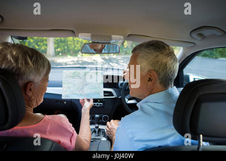 Vue arrière du couple discutant sur la carte en voiture Banque D'Images