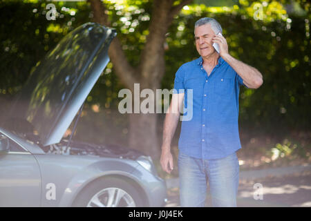 Confused senior man talking on phone par voiture panne Banque D'Images