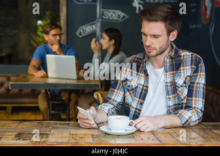 L'homme à l'aide de téléphone mobile tout en ayant le café dans cafÃƒÂ© Banque D'Images