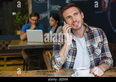 Man talking on mobile phone while having coffee in cafÃƒÂ© Banque D'Images
