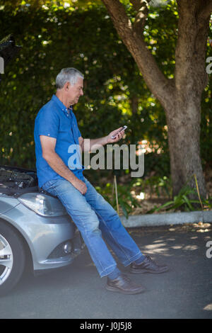 Man looking at mobile phone après la panne de voiture Banque D'Images