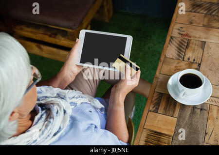 High angle view of woman holding tablet et une carte de crédit alors qu'il était assis au café shop Banque D'Images