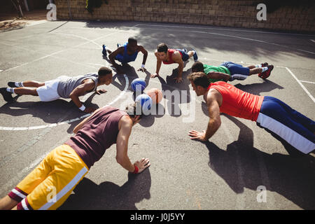 Les joueurs de basket-ball faisant des pompes jusqu'à l'exercice de basket-ball extérieur Banque D'Images