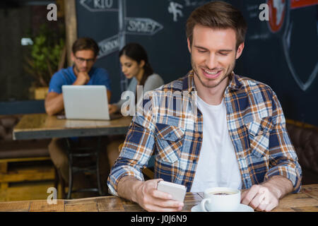 L'homme à l'aide de téléphone mobile tout en ayant le café dans cafÃƒÂ© Banque D'Images