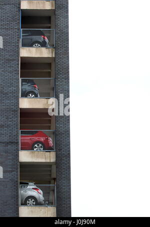 Composition verticale photographie de la fin d'un parking à étages contre un ciel blanc, avec les extrémités arrière des véhicules sur tous les étages Banque D'Images