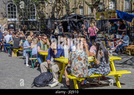 Les gens assis dehors à manger tables sur l'alimentation de rue Brick Lane dans l'Est de Londres. Banque D'Images