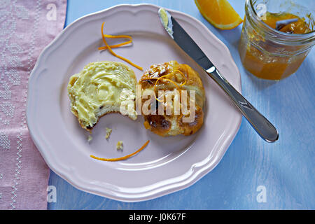 Hot cross bun avec du beurre et de la marmelade d'orange Banque D'Images