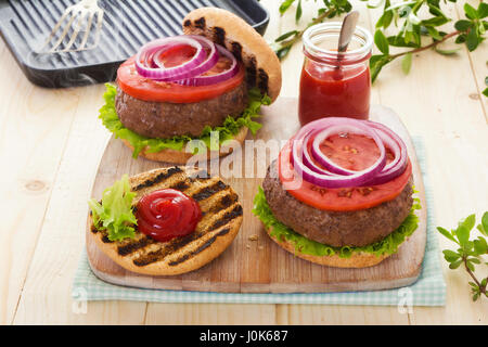 Burger avec laitue tomate oignon rouge sur les petits pains grillés avec du ketchup Banque D'Images