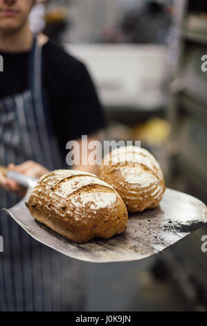 Baker en tenant des baguettes de pain frais du four Banque D'Images