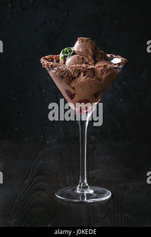 Verre à cocktail avec de la crème glacée au chocolat mini boulettes avec les framboises et menthe noir sur fond de bois brûlé. Banque D'Images