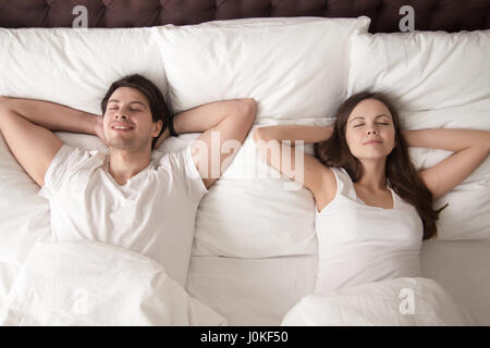 Heureux l'homme et la femme au lit avec les yeux fermés Banque D'Images