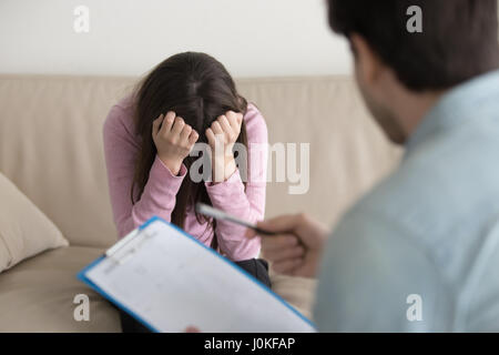 Appuyée de pleurer femme assise, la tête baissée, psychologue Banque D'Images