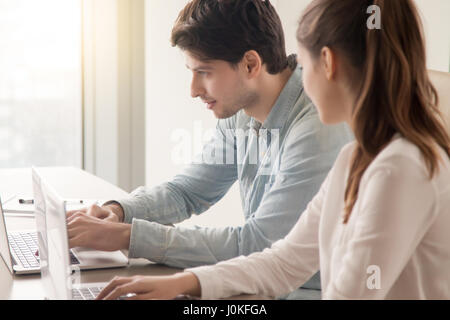 Les employés de bureau masculins et féminins à l'aide de deux ordinateurs portables sur le lieu de travail Banque D'Images