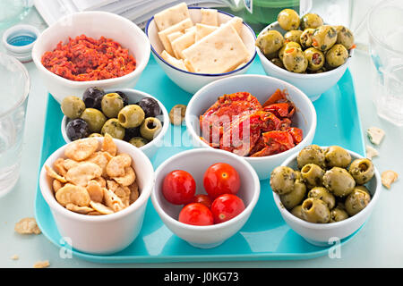 Des tapas espagnoles sur le bac bleu - pesto rouge, olives, tomates cerises, pesto rouge, craquelins Banque D'Images