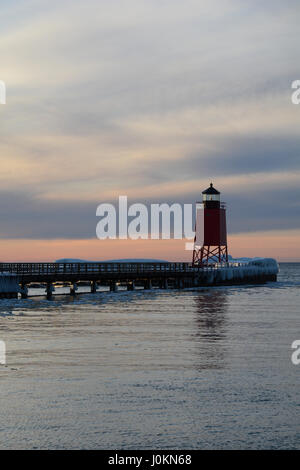 Le soleil qui s'allume une doublure de glaçons avec un phare rouge pier. Le phare de la jetée sud, Charlevoix, Québec Banque D'Images