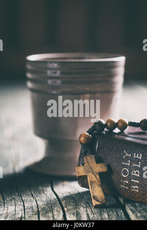 Chapelet, sainte bible et coupe de vin sur la table en bois. Banque D'Images