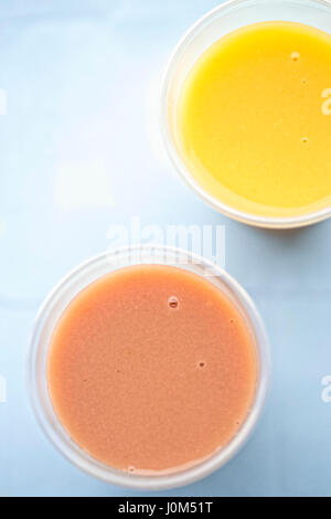 Banane-fraise et orange Smoothie mangue dans des gobelets en plastique Banque D'Images