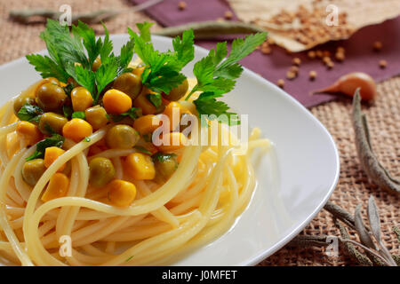 Spaghettis aux petits pois (conserve), le maïs et les feuilles de persil sur la plaque Banque D'Images