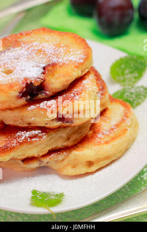 Détail de blinis empilées (à partir de farine blanche, avec prune) garni de sucre en poudre et la menthe sur fond flou Banque D'Images