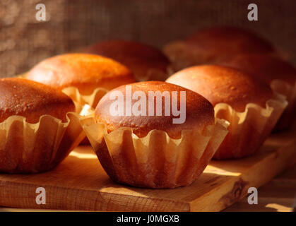 Muffins faits maison dans un moule de papier moules à pâtisserie sur une planche de bois. L'accent sur premier avion muffin. Banque D'Images