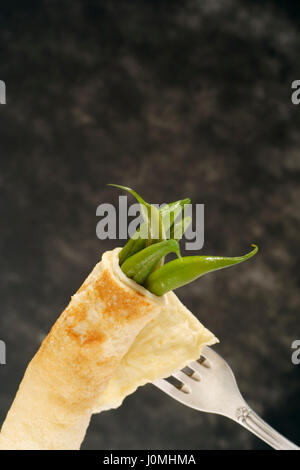 Les gousses de haricots verts cuits enveloppés dans pancake sur argent fourche antique avec copie espace en haut. Banque D'Images