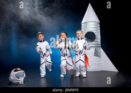 Deux petits garçons et filles dans les combinaisons spatiales exécutant and smiling at camera Banque D'Images