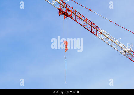 La construction rouge gris avec grue à tour de bras et l'arbre isolé sur ciel bleu avec des nuages blancs de fond, détail Banque D'Images