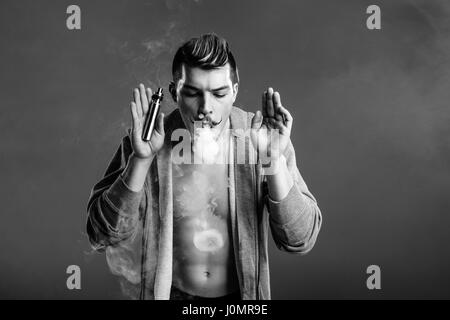 Photo en noir et blanc de jeunes bel homme seine et faire des cercles de fumée Banque D'Images