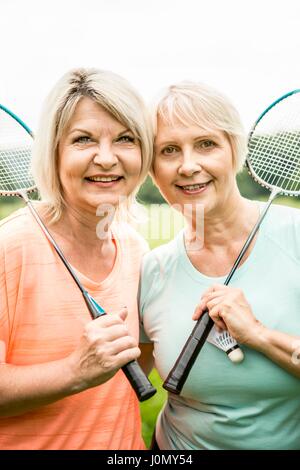 Deux femmes occupent des raquettes de badminton, en souriant. Banque D'Images