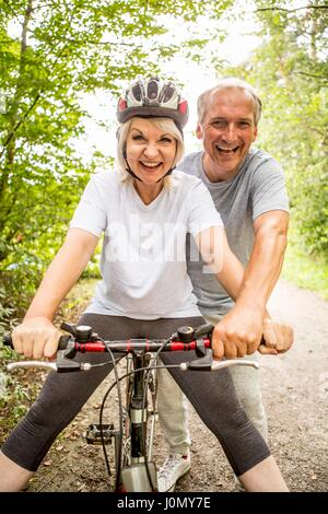 Senior woman on bike, mature man aidant. Banque D'Images