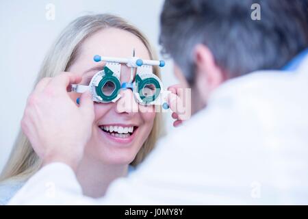 L'optométriste d'effectuer l'essai d'oeil de la jeune femme. Banque D'Images