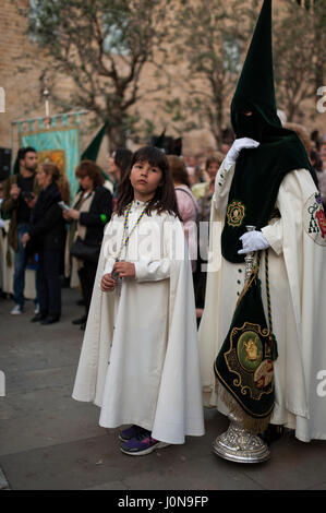 Espagne, Barcelone. 14 avril, 2017. Un jeune pénitent de la "Hermandad de Nuestro Padre Jesús del Gran Poder y María Santísima de la Esperanza Macarena' accompagne sa mère à capuchon pendant la procession de la Semaine Sainte. Crédit : Charlie Perez/Alamy Live News Banque D'Images