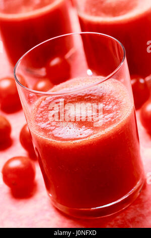 Avec le verre de jus de tomates fraîches sur fond rouge Banque D'Images