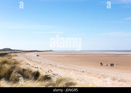 Scène de plage people walking dogs au Holkham Beach, une grande plage de sable avec des dunes sur la côte nord du comté de Norfolk, UK Banque D'Images