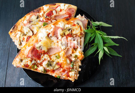 Tranches de pizza avec feuilles de marijuana sur une plaque Banque D'Images