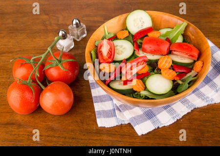 Une salade verte fraîche de laitue, épinards, concombres, carottes, tomates et poivrons dans un bol en bois Banque D'Images