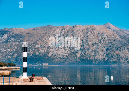 Phare noir et blanc dans la mer. Prcanj, baie de Kotor, Monténégro. Banque D'Images