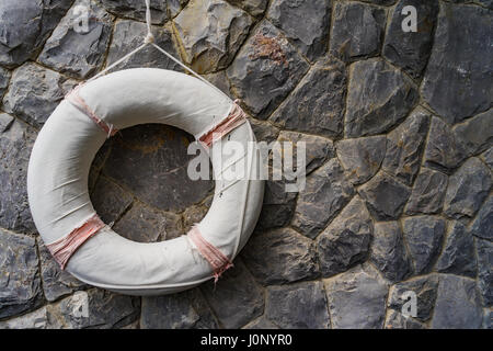 Caoutchouc de sauvetage, bouée accroché sur un mur de pierre, mur de pierre Banque D'Images