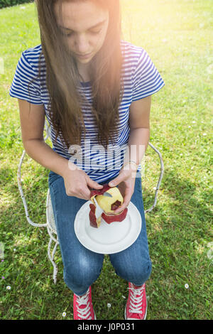 Young woman peeling une pomme dans le jardin Banque D'Images