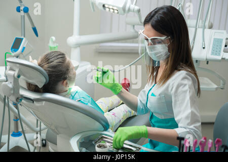 Femme Dentiste Contrôle de petite fille malade Banque D'Images