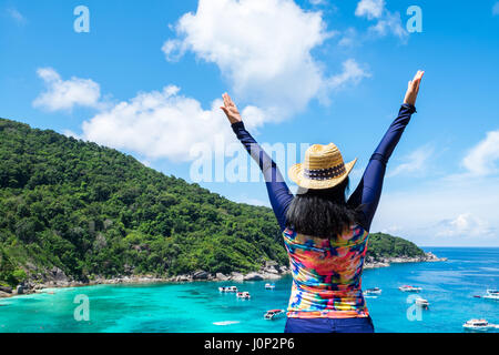 Traveller femme avec maillot coloré les bras levés au ciel en haut de montagne avec vue sur l'océan bleu et la vitesse bateau en mer vacances d'été,voyager Banque D'Images
