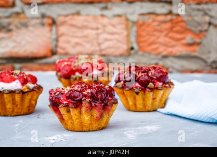 Des gâteaux de sweet berry paniers avec les cerises et les framboises sur l'arrière-plan d'un mur de déroulage. Banque D'Images